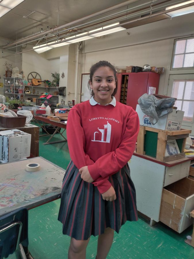 Julia Esparza smiling in the art room, surrounded by workstations and art pieces. Ms. Jensen selected Esparza for artist of the month because of her unique style and fearless experimentation. Photo courtesy of the author.