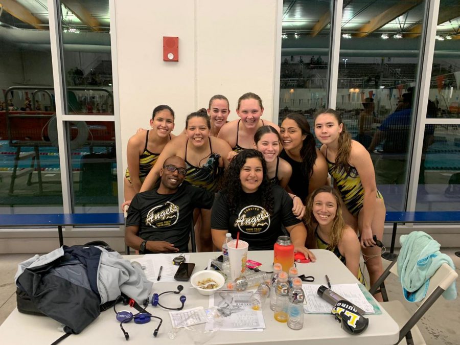 Sara Morales is gathered around by her new swim family, and Coach Wright to the right of her. Sara Morales is taking the times of the swimmers at the Del Valle meet.