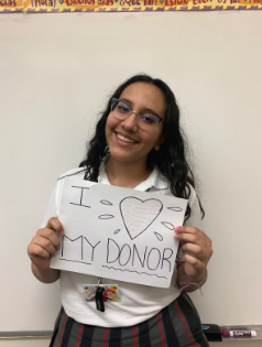 Arissa Ramirez poses for a photo while holding a sign saying, “I love my donor.” Ramirez’s education at Loretto Academy is possible through the generosity of her donor. Photo courtesy of the author.