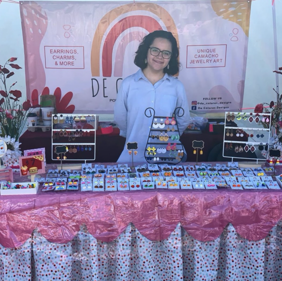 Elisa Camacho at the Super Valley market selling her custom earrings and accessories. The variety of her product is displayed on the table.