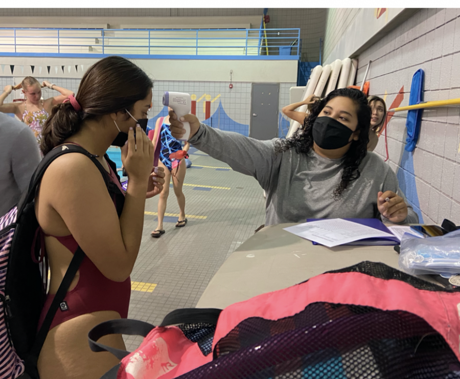 Assistant+swim+coach%2C+Sara+Morales%2C+checking+the+temperature+of+senior+swimmer%2C+Paulina+Quiroz.+Athletes+must+now+go+through+checks+before+entering+the+pool+and+participating+in+sports.%0A