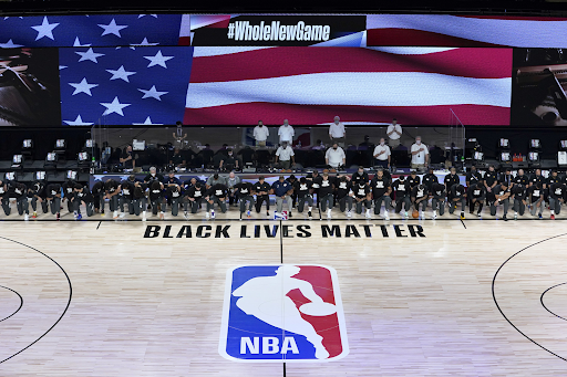 Players and staff kneeling before the NBA reopens after negotiations with owners. After the shooting of Jacob Blake, the NBA was halted in order to protest police brutality.
