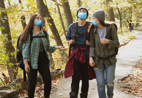 Three young adults gather together in a socially distanced setting to get some time outside. Connecting with friends, and being outside have medical benefits. 

