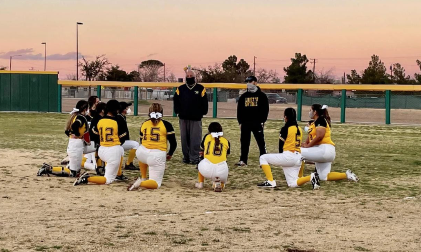 The team kneels down as their coaches talk to them during a game. The girls represent Loretto with their gold and black uniform and prepare for a great game. 