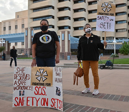 Protestors in Albuquerque, New Mexico, hold signs calling for workplace safety after the death of Halyna Hutchins on the movie set of “Rust . Hutchins, a Ukrainian cinematographer, died at age 42. Photo courtesy of BBC News