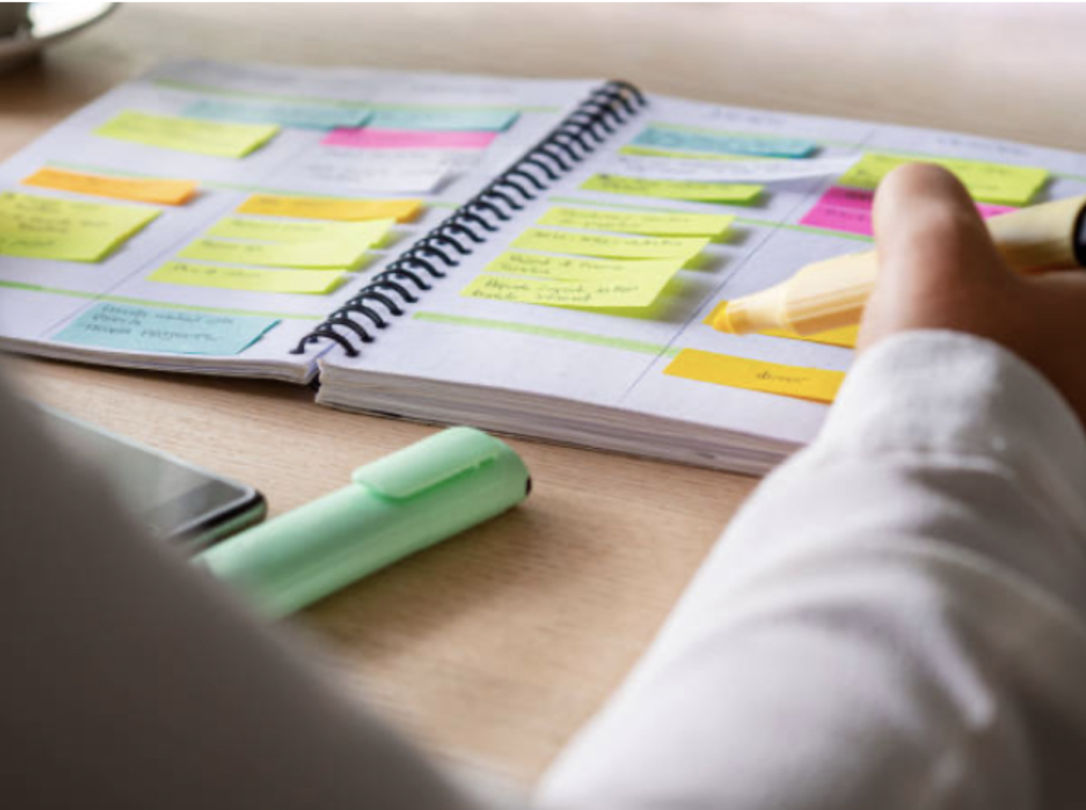 A person organizing and highlighting in their notebook. By keeping everything organized, the person has a set schedule of their study session. Photo courtesy of flickr.