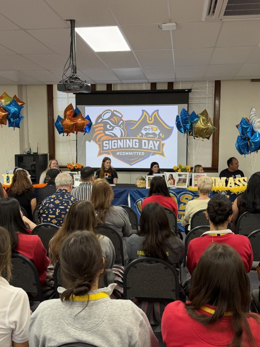 Monse and Addison signing their contracts to play volleyball at their respective schools. Their loved ones watch from the crowd, proud of their achievements. Photo courtesy of Mrs. Munoz.